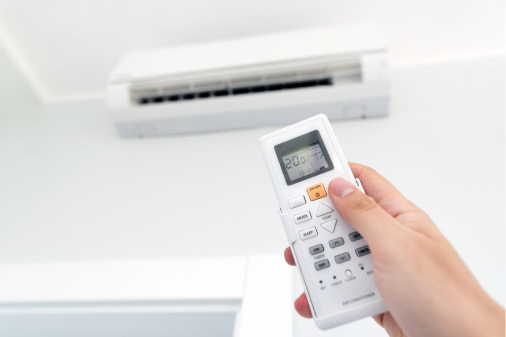 Hand adjusting an air conditioner remote in a poorly insulated home | Brisbane Insulation